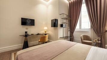 Une chambre d’hôtel avec un lit, un bureau avec une lampe, une chaise, un téléviseur et une fenêtre avec des rideaux.