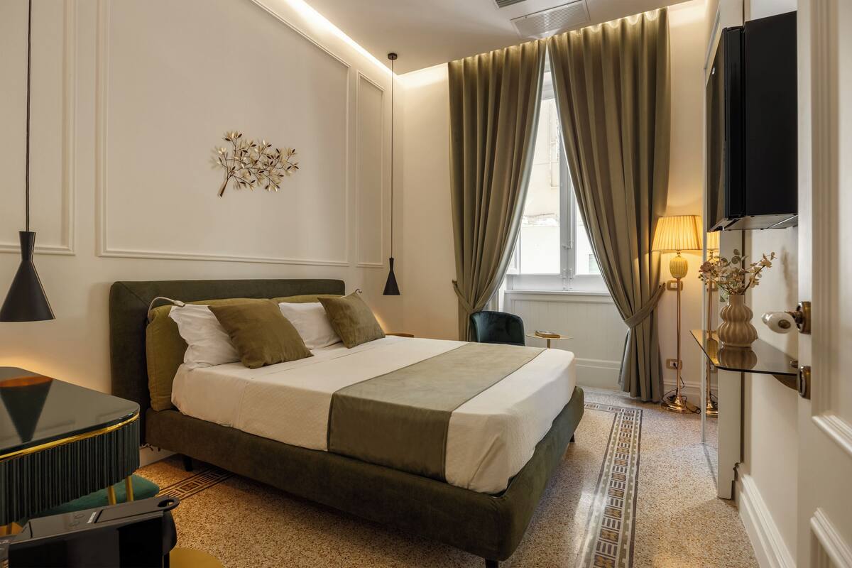 A neatly arranged hotel room with a large bed, a bedside table, a lamp, and a television.