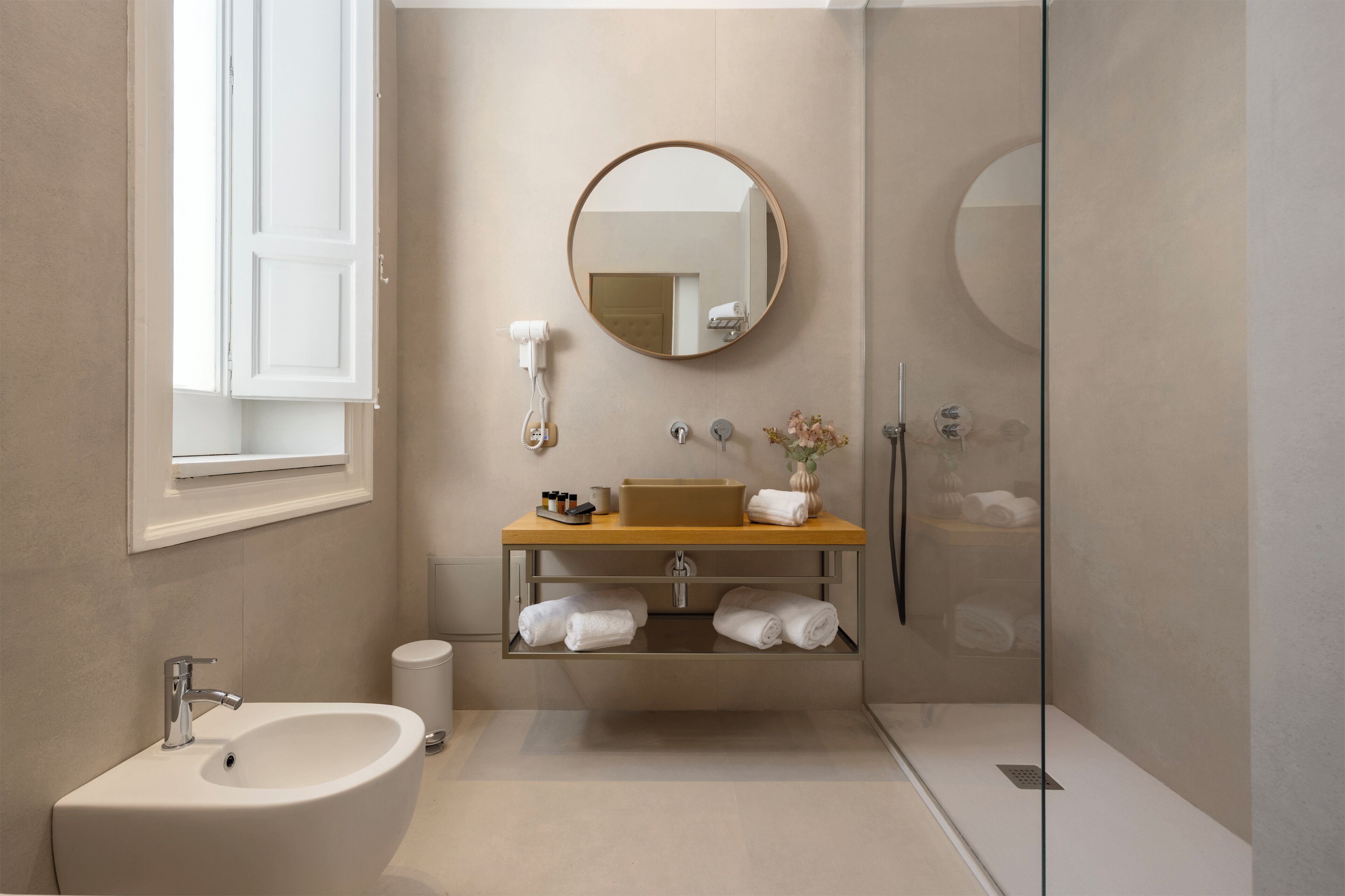 A modern bathroom with a sink, mirror, and glass shower enclosure.