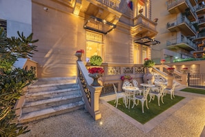 A hotel courtyard with marble steps, outdoor seating, and a well-maintained lawn. - Villa libertà (Palermo)
