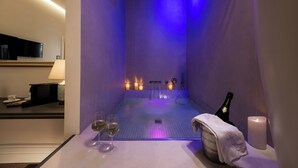 Een spa-ruimte met een bad, kaarsen en champagne.