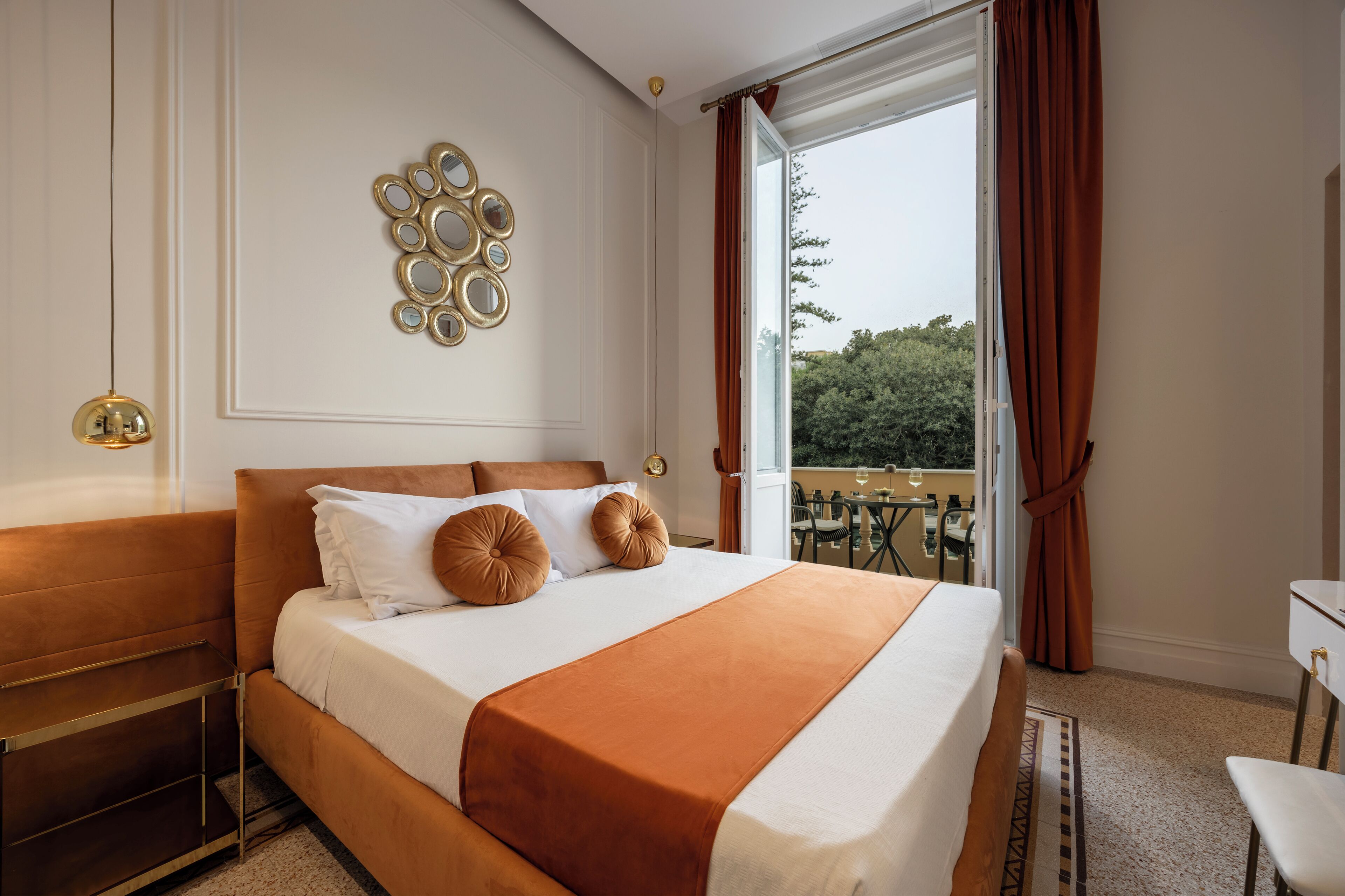 A hotel room with a large bed, a desk, and a balcony with a view of trees.