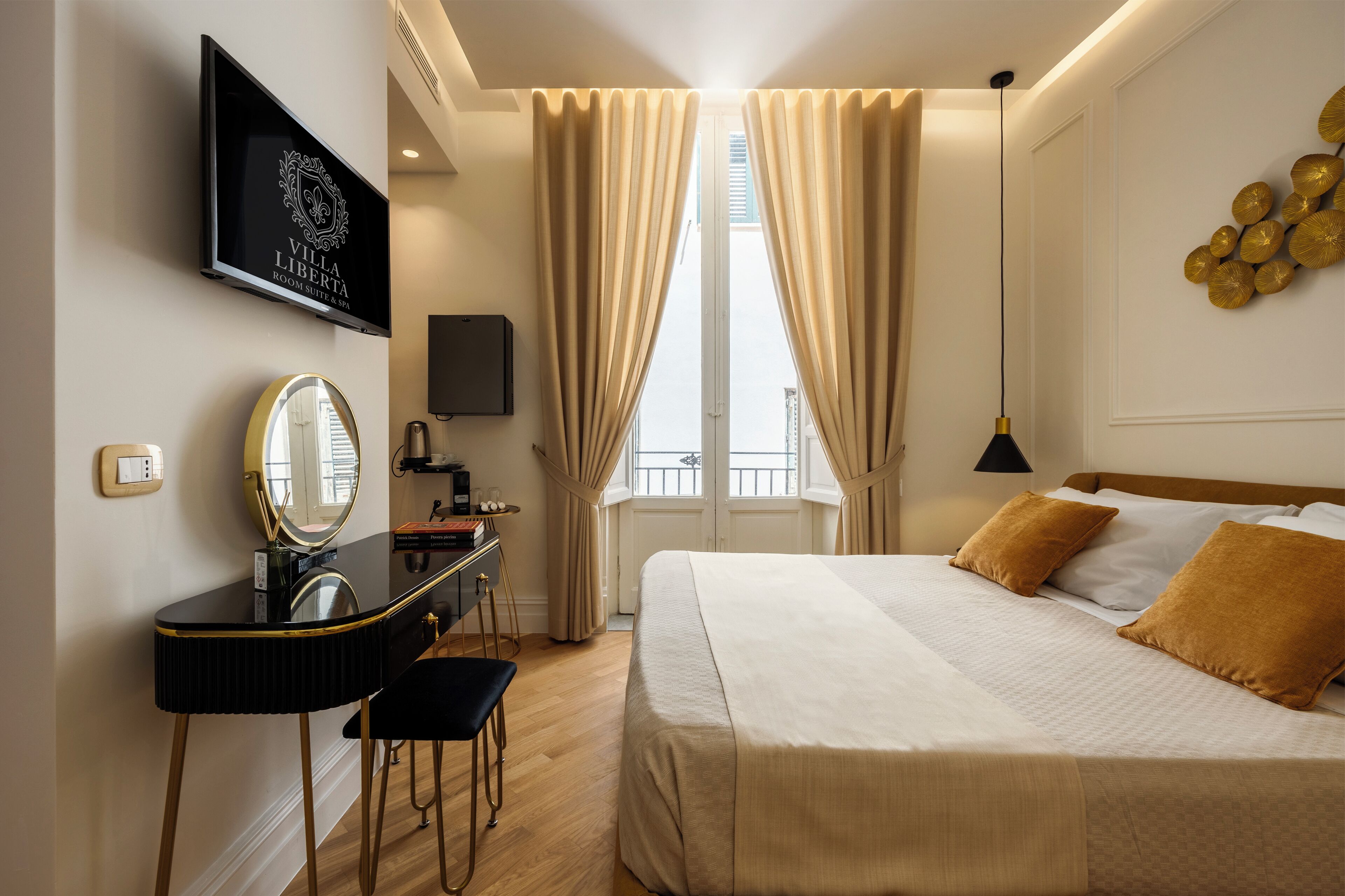 A hotel room with a bed, a desk with a mirror, a television, and a window with curtains.