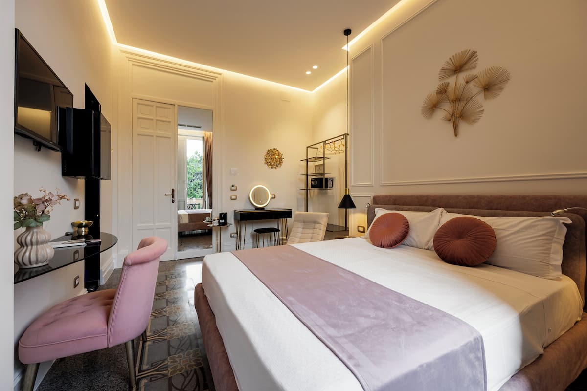 A modern bedroom with a large bed, a desk, a chair, and a TV mounted on the wall.