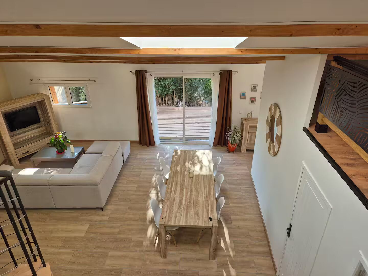 Amplia sala de estar con una mesa de comedor de madera, un sofá y un televisor instalado en una pared de madera.