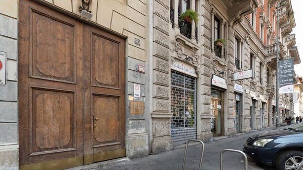 A building with large wooden doors, a metal gate, and a sign for 'Livinghouse.' - GuestHost - Milan City Studies Balcony Apt (Milan)
