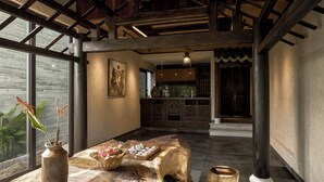 Una habitación amplia con una mesa de madera, un florero con flores y vistas a una cocina tradicional.