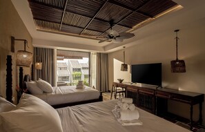 A hotel room with two beds, a TV, a desk, and a ceiling fan.