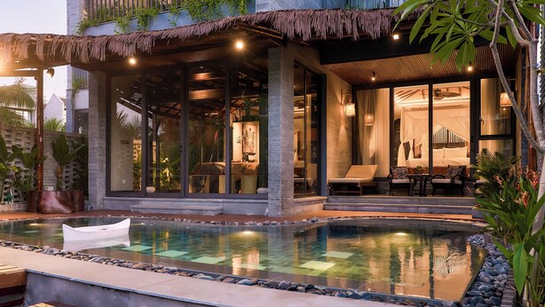 Un hotel moderno con piscina, zona de estar al aire libre y una entrada bien iluminada.