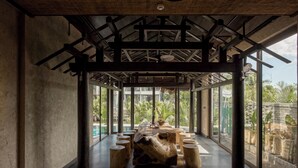Un espacio interior amplio con techo alto, ventanas grandes y una escultura de madera en el centro.