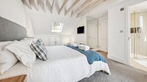 A bedroom with a bed, a TV, a shower, and a door to a bathroom. - Stunning 3-Bedroom Apartment in Hampstead (London)