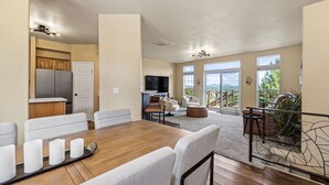 Un vaste espace de vie comprenant une table à manger, des canapés et un balcon avec vue.