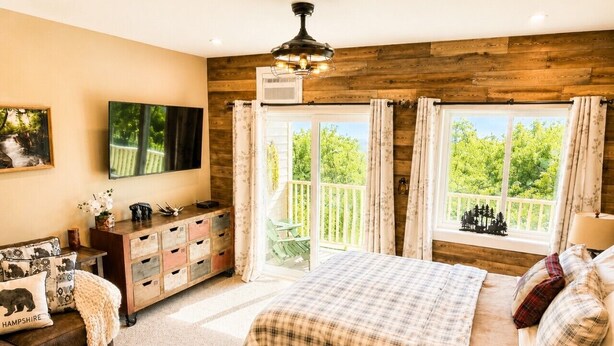 A bedroom with a bed, a dresser, a TV, and a balcony with curtains.