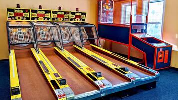 A bowling alley with multiple lanes, a scoreboard, and a ball return system.