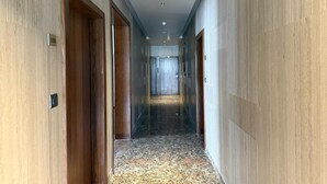 A hallway with wooden doors, a carpeted floor, and a ceiling with recessed lighting. - Hotel Acksia Inn (Udaipur)