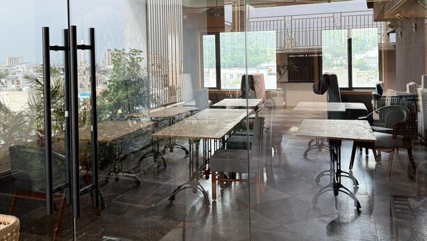 A modern conference room with glass walls, a high ceiling, and a view of the cityscape. - Hotel Acksia Inn (Udaipur)