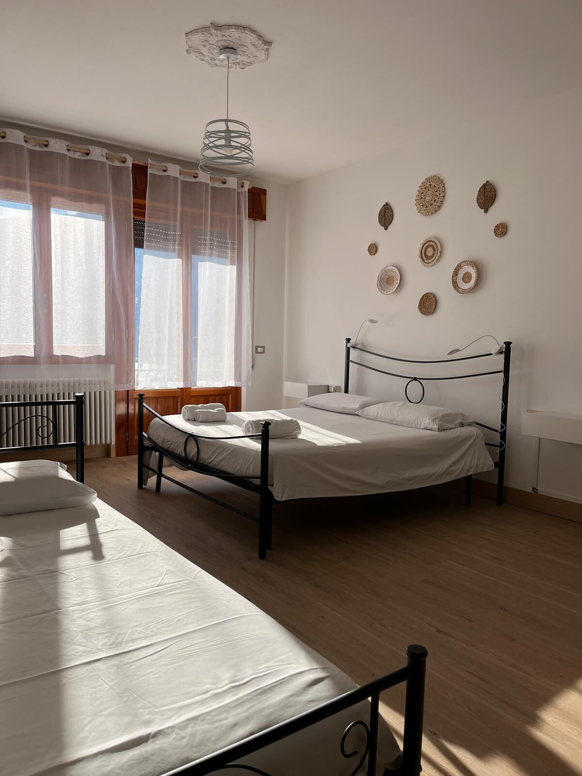 Un dormitorio con cama, una silla y una ventana con cortinas.