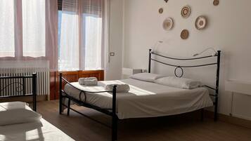 Un dormitorio con cama, una silla y una ventana con cortinas.