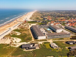 An aerial view of a coastal hotel with multiple buildings, a beach, and a dune system. - 6 Person Holiday Home on a Holiday Park in Blokhus (Blokhus)