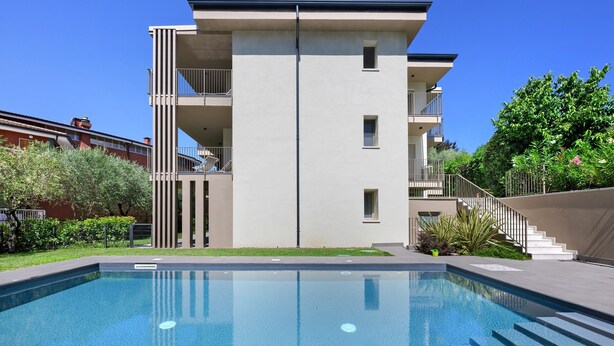 Ein modernes Gebäude mit Schwimmbad, Balkonen und einer Treppe, die zu einer oberen Ebene führt.
