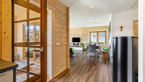 A wooden interior with a dining area, kitchen, and a large black refrigerator. - Holiday Home 'Ferienhaus Traum Teufel' with Terrace, Garden and Wi-Fi (Hettingen)