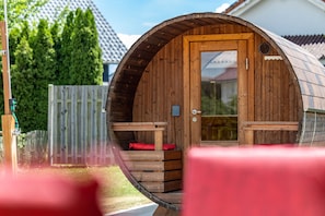 Une cabane en bois avec un toit incurvé, une porte et un petit porche doté d’un banc.