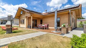 A wooden house with a patio, outdoor seating, and a chimney.