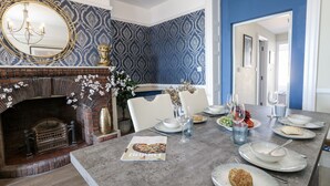 Un coin repas agrémenté d’une cheminée en briques, d’un papier peint à motifs et d’un mur d’accent bleu.