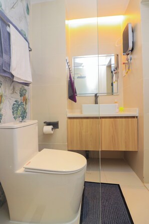 A modern bathroom with a toilet, sink, and mirror. - Pazoori Stays at Artesano Apartments (Syokimau)