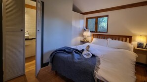 A bedroom with a bed, a nightstand, a window, and a door. - The Stable | Oak-Frame Kent hideaway · Hot Tub (Cranbrook)