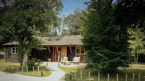 A rustic cabin with a wooden exterior, a covered porch, and a gravel pathway leading to it. - The Stable | Oak-Frame Kent hideaway · Hot Tub (Cranbrook)