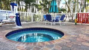 A hot tub with a pool rule sign, blue chairs, and a white fence. - August Beach Escape – Special Rates Available! (Treasure Island)