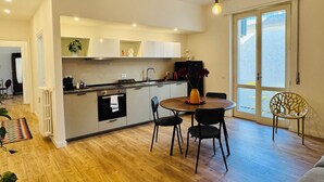 Ett modernt kök med matplats, trägolv och ett stort fönster.