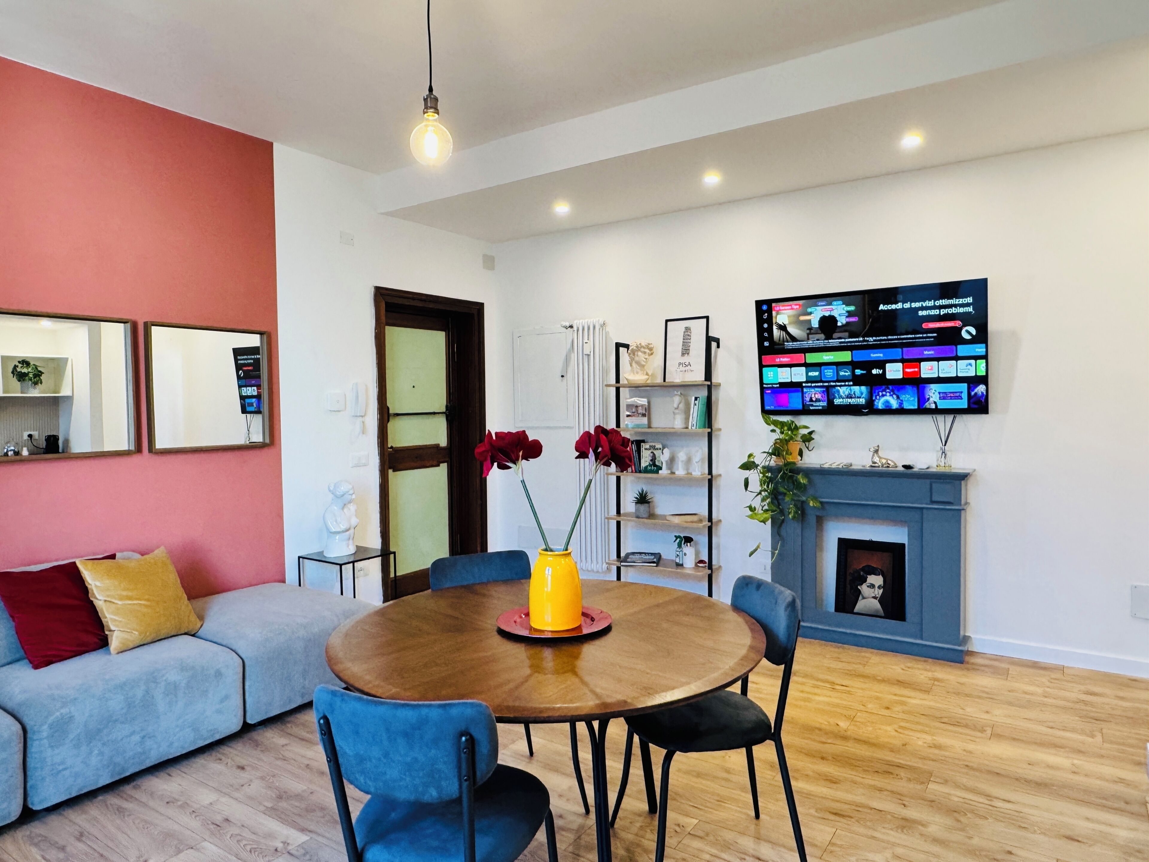Ein modernes Wohnzimmer mit einer Couch, einem runden Holztisch, Stühlen, einem Fernseher und einem Kamin.