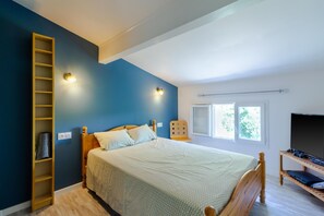 A bedroom with a bed, a wooden ladder, a shelf, a window, and a television.