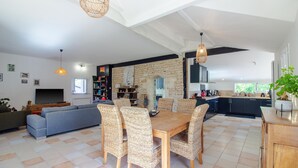Un salon moderne comprenant un canapé, une table à manger et des chaises, un coin cuisine et un mur d’accent en pierre.