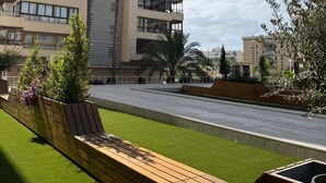 A modern apartment building with multiple balconies, a well-maintained lawn, and a wooden deck.
