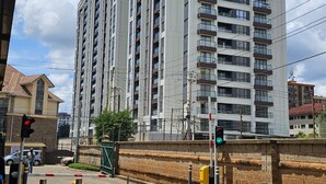 Un immeuble résidentiel à plusieurs étages, doté de balcons, d’une entrée sécurisée et d’un feu de signalisation.