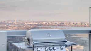 Un barbecue installé sur un toit, offrant une vue sur le paysage urbain et une rivière.