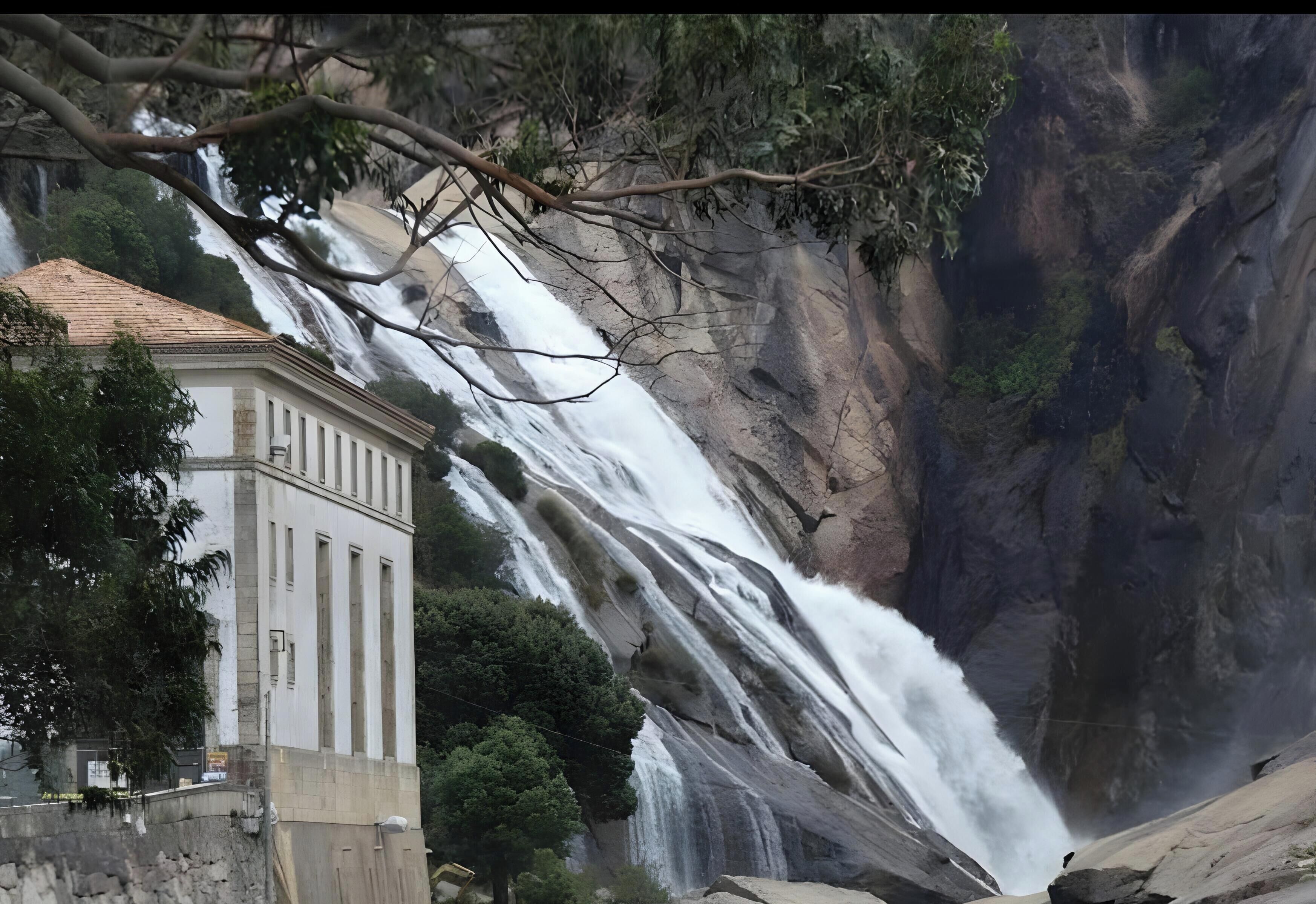 A waterfall cascading down a rocky cliff with a building in the foreground.