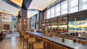 Un área de bar moderna con una barra larga, taburetes y una estantería bien surtida de botellas de licores.