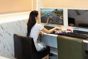 Una persona juega un videojuego de carreras en una configuración con dos monitores.