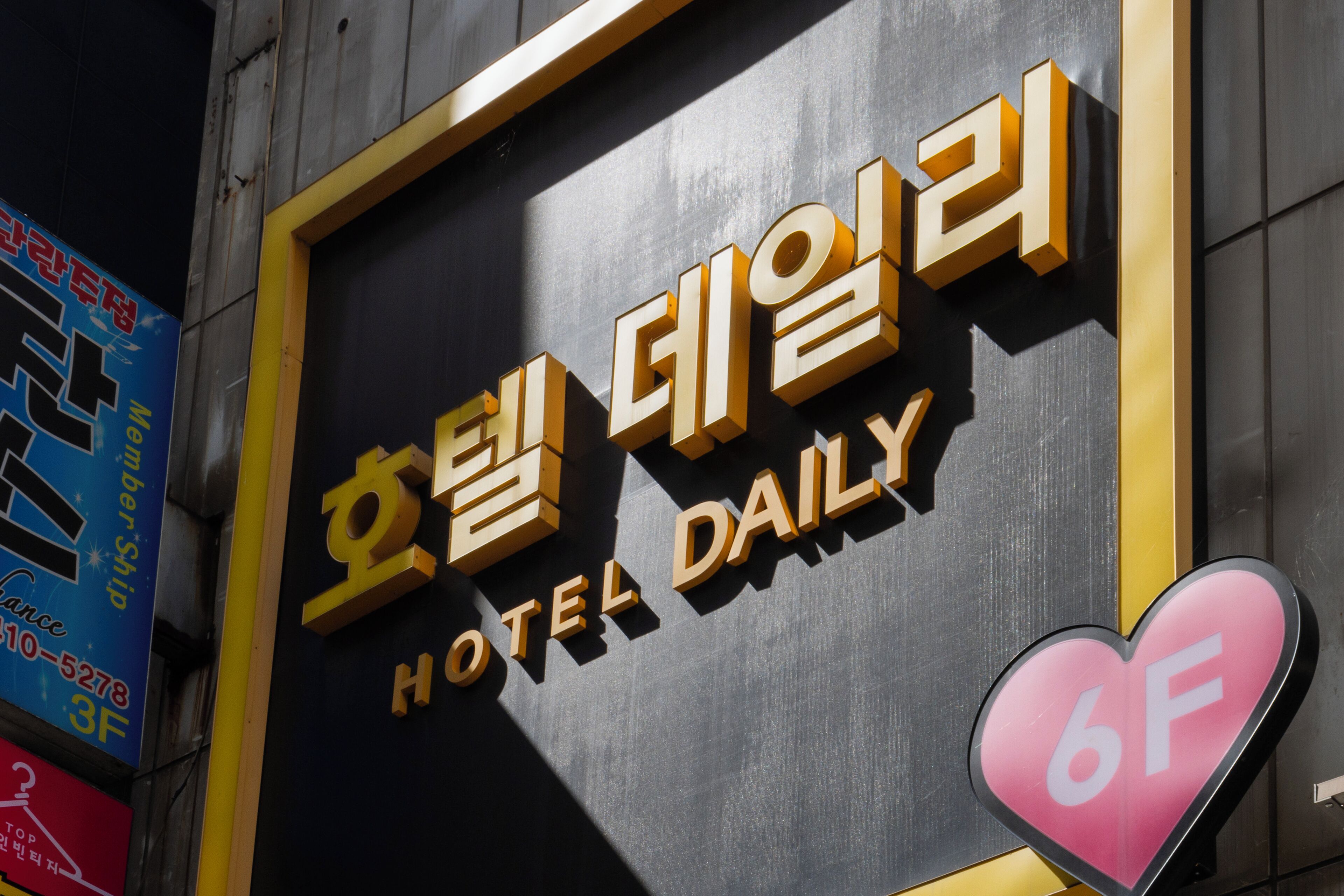 Placa de hotel com o nome 'HOTEL DAILY' e uma placa em formato de coração com '6F' indicando o andar.