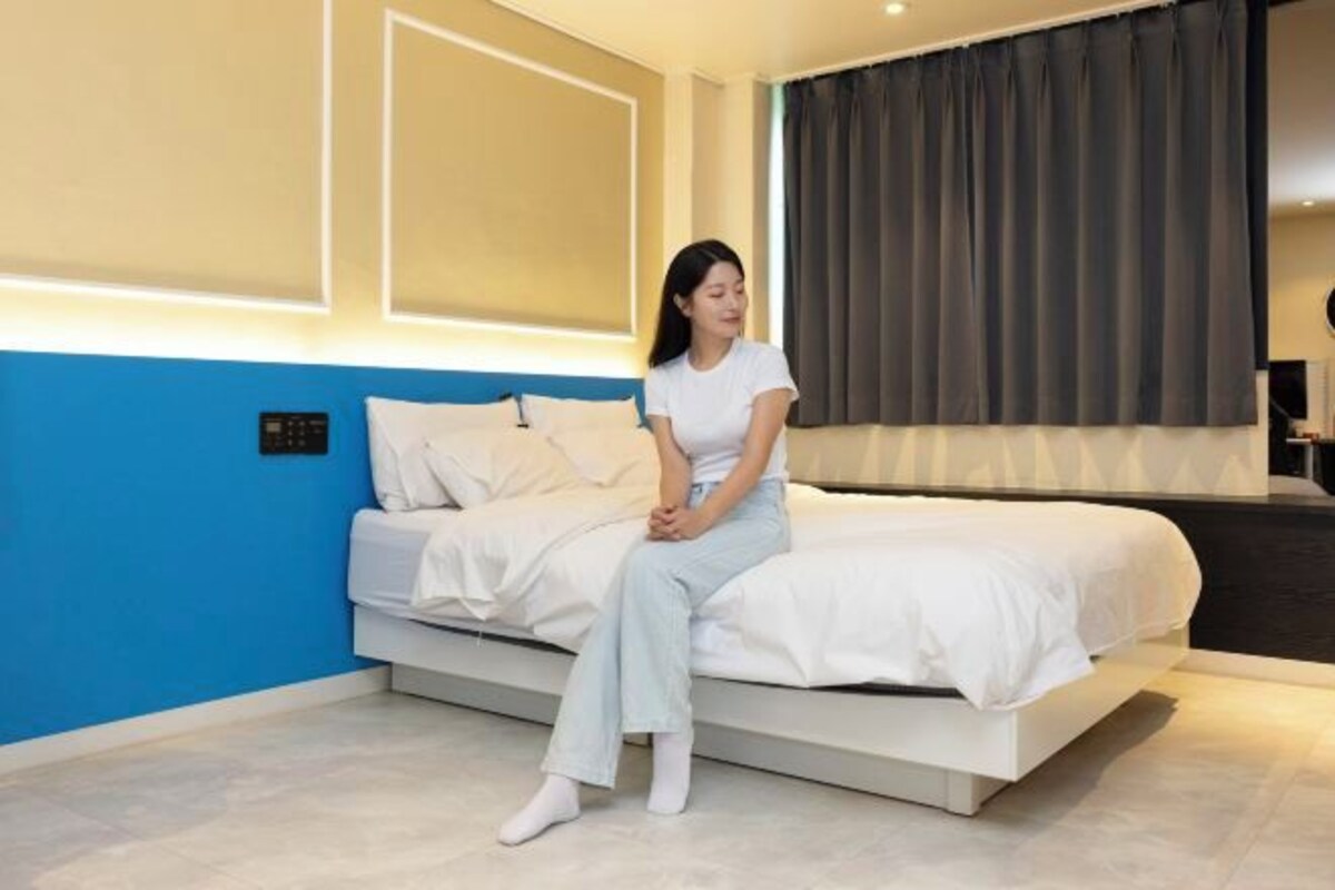 Un dormitorio moderno con cama, mesita de noche y un amplio ventanal con cortinas.