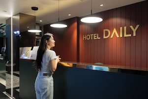Un mostrador de recepción de hotel con un letrero que dice "HOTEL DAILY" y una pantalla digital que muestra información.