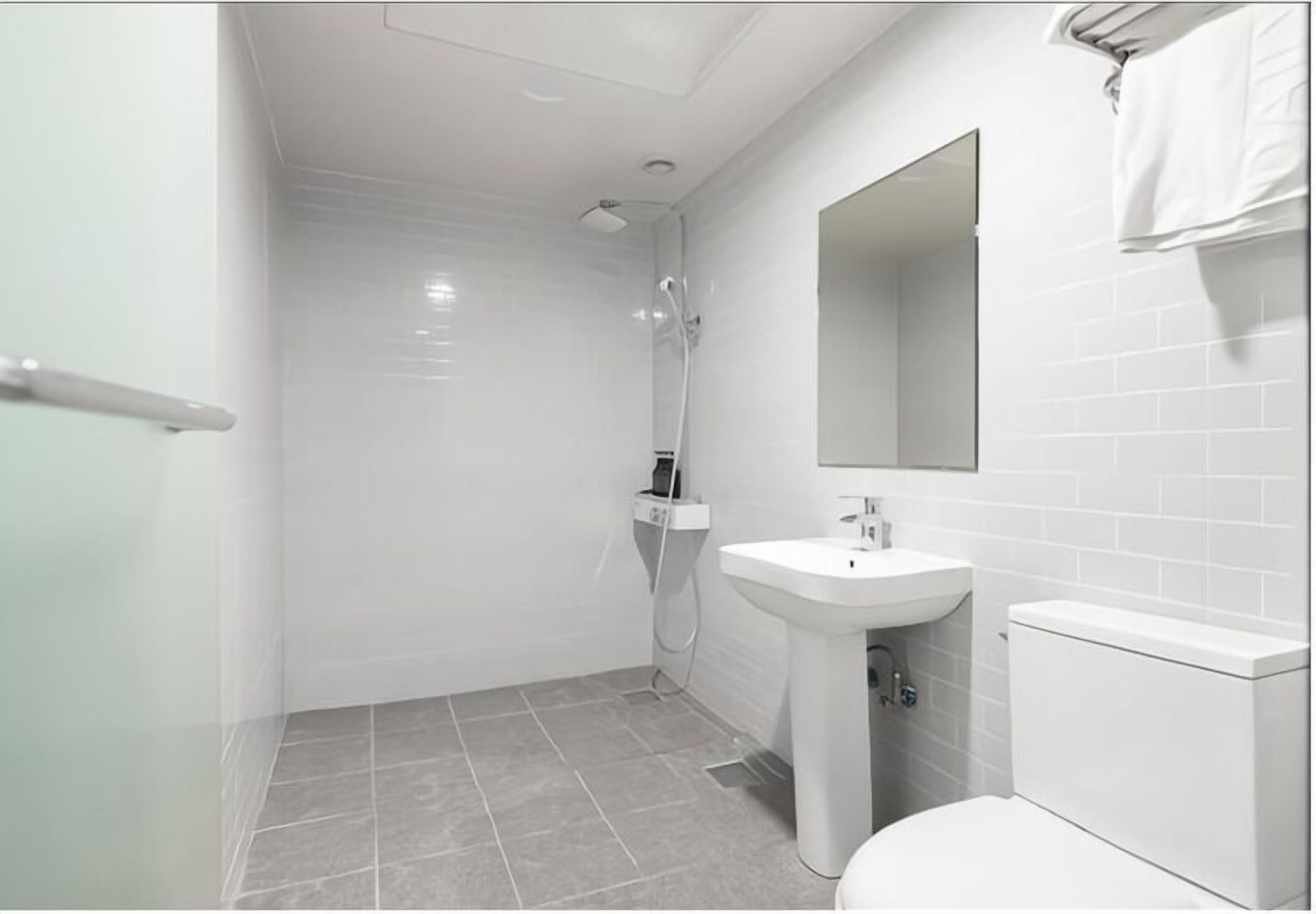 A modern bathroom with a shower, sink, and toilet.