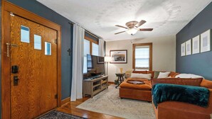 A living room with a wooden door, a ceiling fan, a television, a sofa, and a rug. - 2 Bed 1 Bath home by College Hill and Hospitals (Wichita)