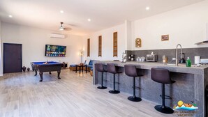 Un salon moderne doté d’une table de billard, d’un coin bar et d’un téléviseur à écran plat fixé au mur.