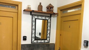 A hallway with two doors, a mirror, and a small shelf with decorative items. - Studio with terrace 10 mn from airport and beach sablette beatch (El-Harrach)