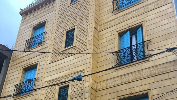 A multi-story building with a beige facade, multiple balconies with black wrought iron railings, and several windows with blue shutters. - Studio with terrace 10 mn from airport and beach sablette beatch (El-Harrach)